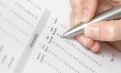 close up view of a hand with a pen filling out a questionnaire.