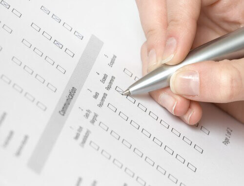 close up view of a hand with a pen filling out a questionnaire.