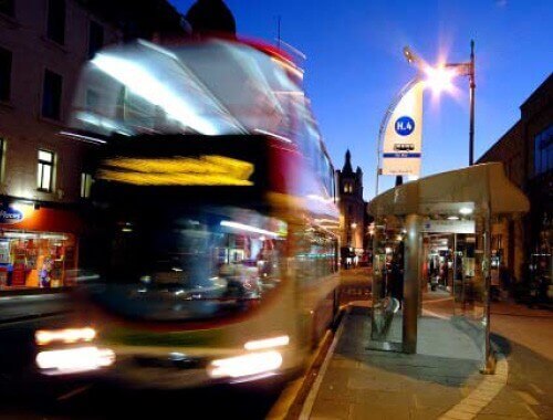 view of an installed bus shelter with a blurred bus leaving the bus stop.