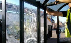 view of a Trueform employee replacing damaged glazed screens on a bus shelter.
