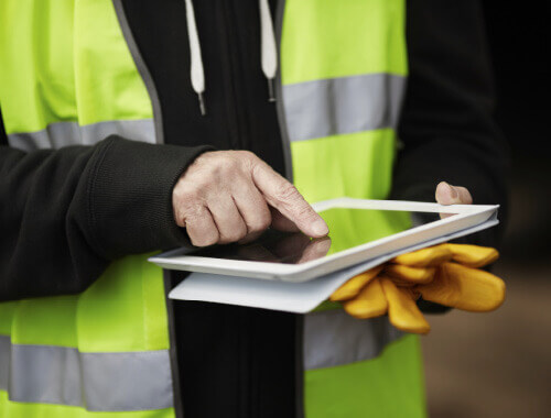 view of Trueform employee in a hi-vis jacket using a tablet.