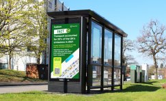 Bus shelter with green sedum roof and digital screen displaying Planet Mark sustainability campaign in Wokingham.