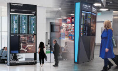 Airport digital displays showing live flight information and passenger wayfinding inside a modern terminal